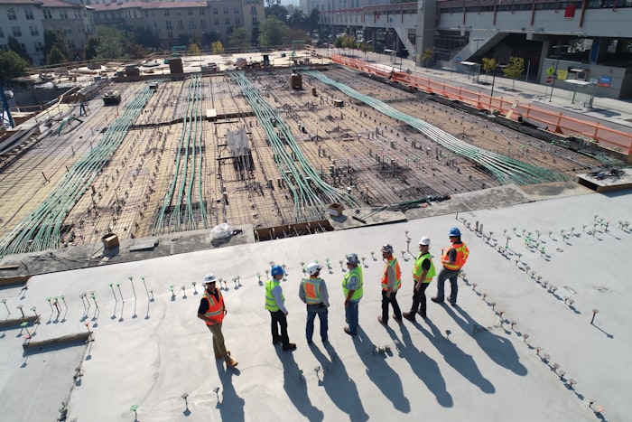 Construction site workers in hi-vis and hard hats surveying a build